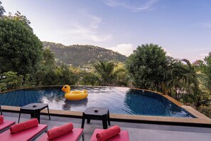 A pool with a yellow inflatable duck, red lounge chairs, and a view of a forested hill. - Private pool villa mountain view / Private chef available (Tambon Chalong)