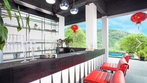 A bar area with red chairs, a glass display case, and a view of greenery outside.