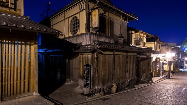 A traditional Japanese building with a wooden exterior, a tiled roof, and a stone base.