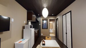 A compact kitchen with a microwave, refrigerator, and a small table with a bottle.