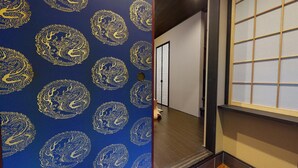 A hallway with a blue wall featuring golden dragon patterns, a wooden floor, and a sliding door leading to another room.