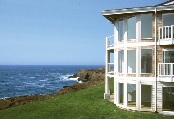 Enjoy ocean views from the upper-level balcony, surrounded by a well-maintained lawn and rocky coastline.