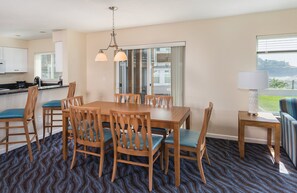 Enjoy meals in this spacious dining area with a large table and six chairs, offering a view of the surrounding landscape.