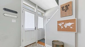 A hallway with two white doors, a world map poster, and a welcome sign. - 3 King Beds/3Baths Spacious by StayStLouis (St. Louis)