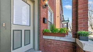 A brick building with a white door and a small porch with potted plants. - 3 King Beds/3Baths Spacious by StayStLouis (St. Louis)