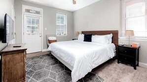 A bedroom with a bed, a nightstand, a ceiling fan, and a window with blinds. - 3 King Beds/3Baths Spacious by StayStLouis (St. Louis)