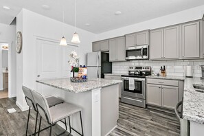 A modern kitchen with granite countertops, stainless steel appliances, and a central island with bar stools.