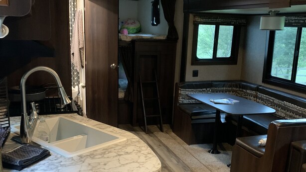 Una cucina compatta con lavello, piano di lavoro e pensili in legno.