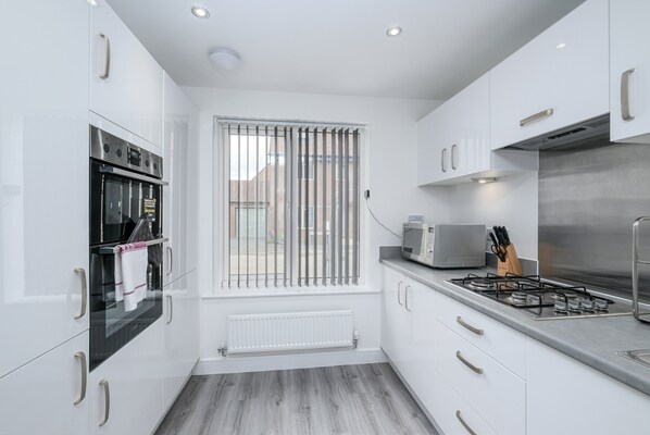 Enjoy cooking in this well-equipped kitchen with a stainless steel range hood, oven, and microwave.