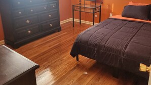 A bedroom with a bed, dresser, and ceiling fan.