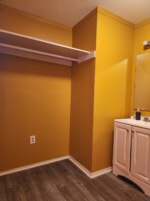 Une salle de bain avec des murs jaunes, un meuble-lavabo blanc et un plancher en bois.