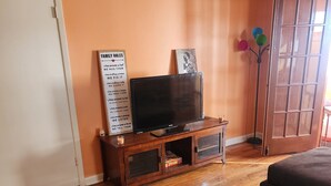 A living room with a wooden entertainment unit, a flat-screen TV, and a bookshelf.