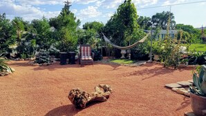 A garden with a hammock, a chair, and a large rock centerpiece. - The Queen's Respite (A) 2 bedrooms, 2 bathrooms (Toquerville)