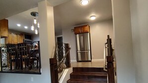 A staircase leading to a kitchen area with a stainless steel refrigerator and wooden cabinets. - The Queen's Respite (A) 2 bedrooms, 2 bathrooms (Toquerville)