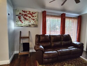 A living room with a brown leather sofa, a wooden ladder, and a red curtain. - The Queen's Respite (A) 2 bedrooms, 2 bathrooms (Toquerville)