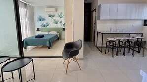 A modern hotel room with a bed, a dining table with chairs, and a small seating area. - Departamento a una cuadra de la playa by Gpsrentas (Mazatlán)