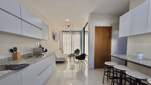 A modern kitchen with a dining area, a sofa, and a bar with stools. - Departamento a una cuadra de la playa by Gpsrentas (Mazatlán)