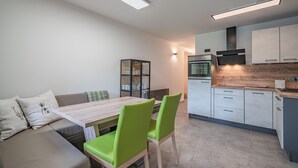 Una cocina moderna con comedor, que incluye una mesa de madera, sillas verdes y un horno empotrado.