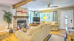 A living room with a fireplace, a sofa, a television, and a ceiling fan. - Secluded Chattanooga Getaway w/ Deck + Yard! (Chattanooga)