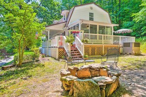 A cabin with a porch, outdoor seating, and a stone fire pit. - Secluded Chattanooga Getaway w/ Deck + Yard! (Chattanooga)