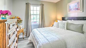 A bedroom with a large bed, a dresser, a nightstand, a window with curtains, and a painting on the wall. - Secluded Chattanooga Getaway w/ Deck + Yard! (Chattanooga)