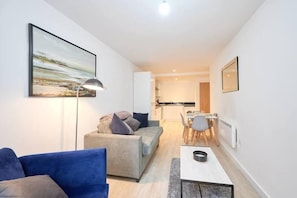 Een moderne woonkamer met een bank, een eettafel en een keuken op de achtergrond.