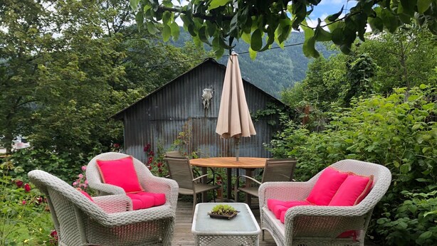 En træterrasse med møbler i flet, et bord og en parasol.