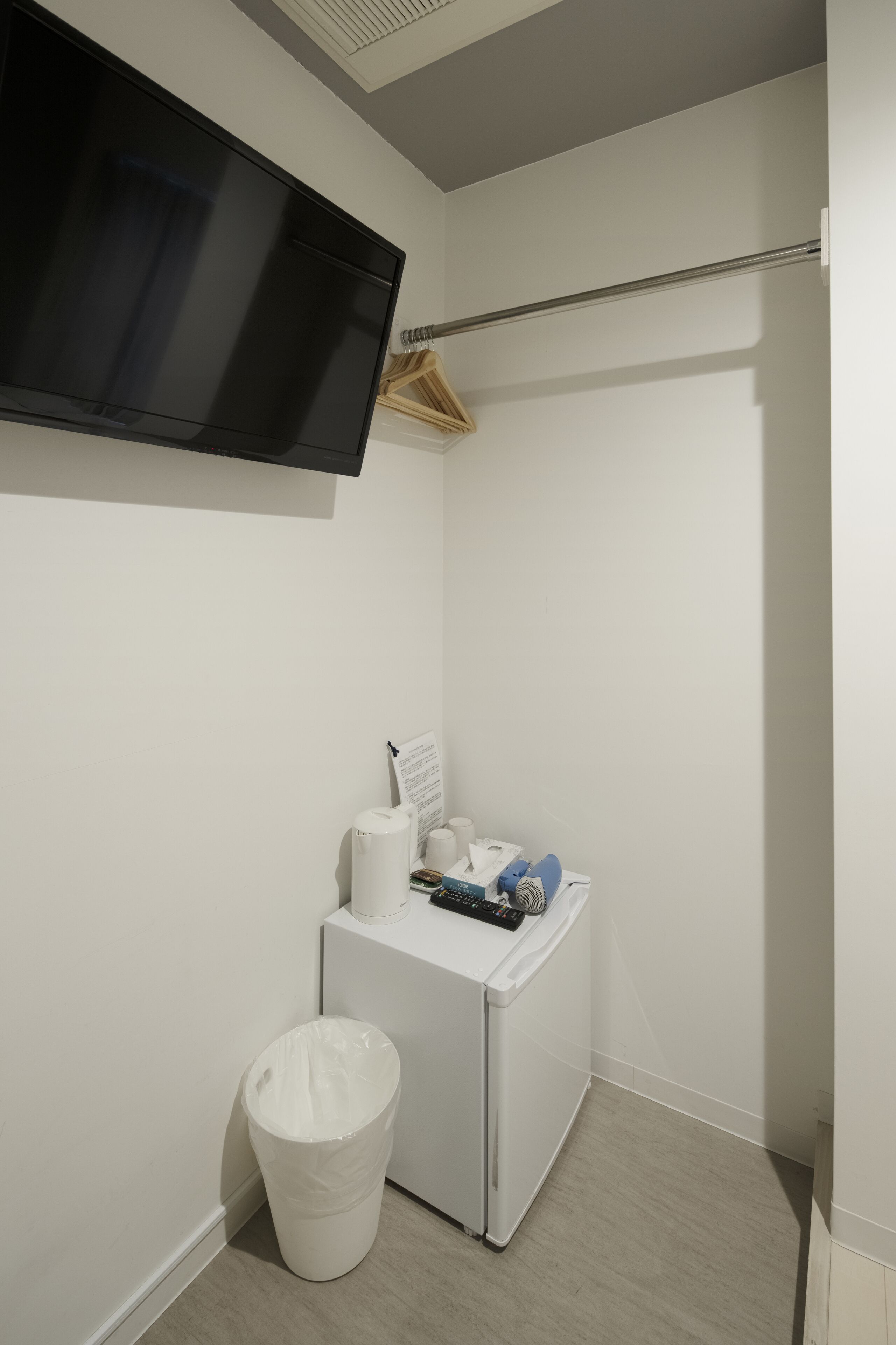 Un baño moderno y funcional con televisión integrada, un pequeño espacio de almacenamiento y un cubo de basura.