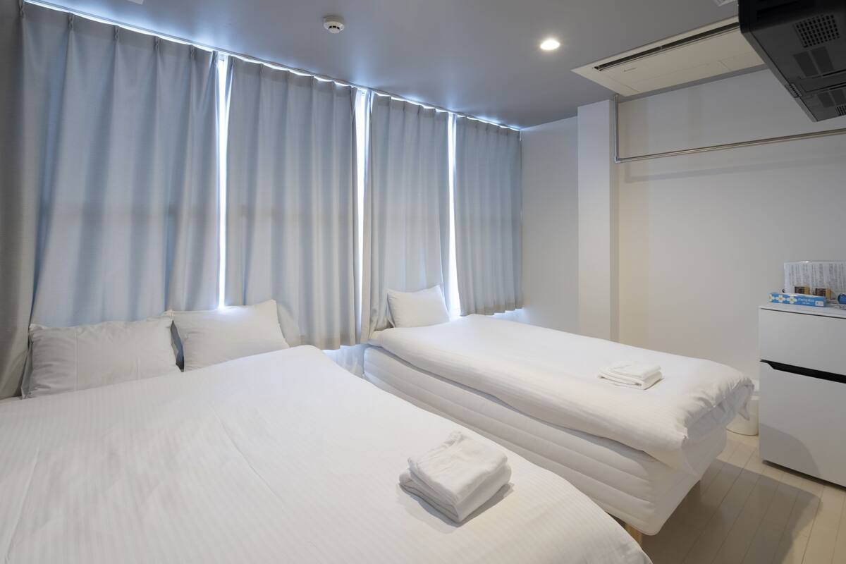 A hotel room with two beds, a desk, and a minibar.