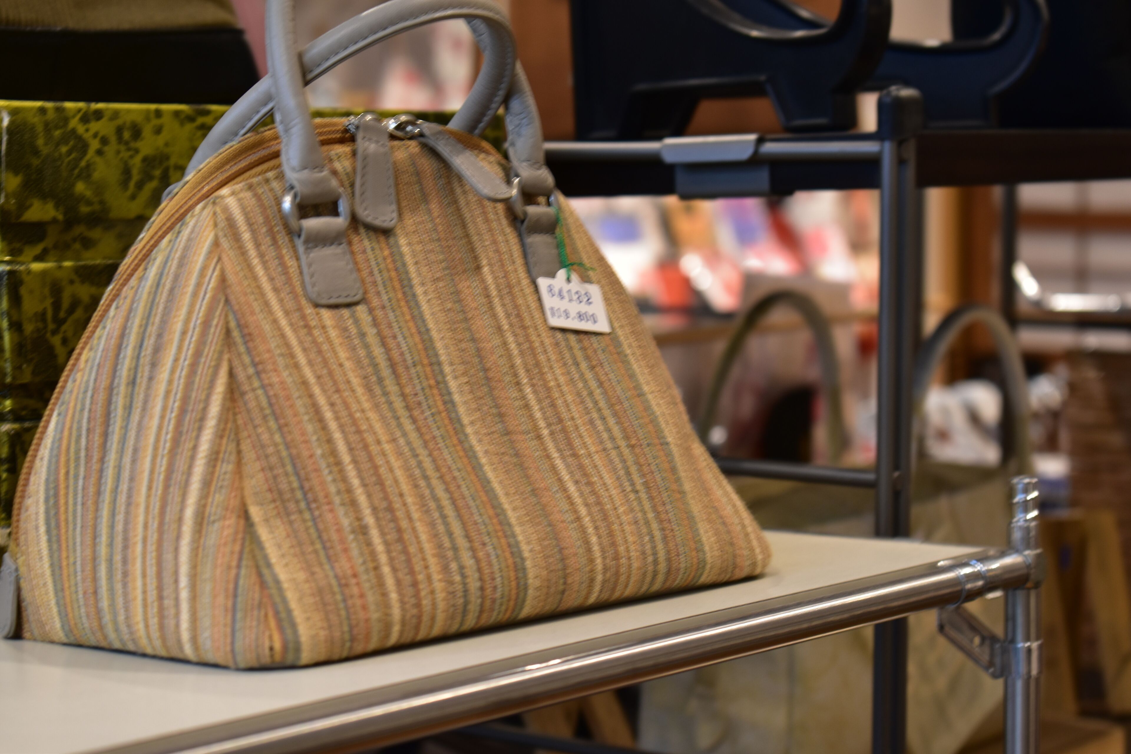 A striped handbag on a display shelf in a store.