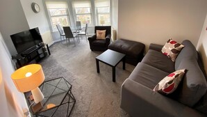 Un salon comprenant un canapé, une table basse, un téléviseur et un coin repas avec des chaises et une table.