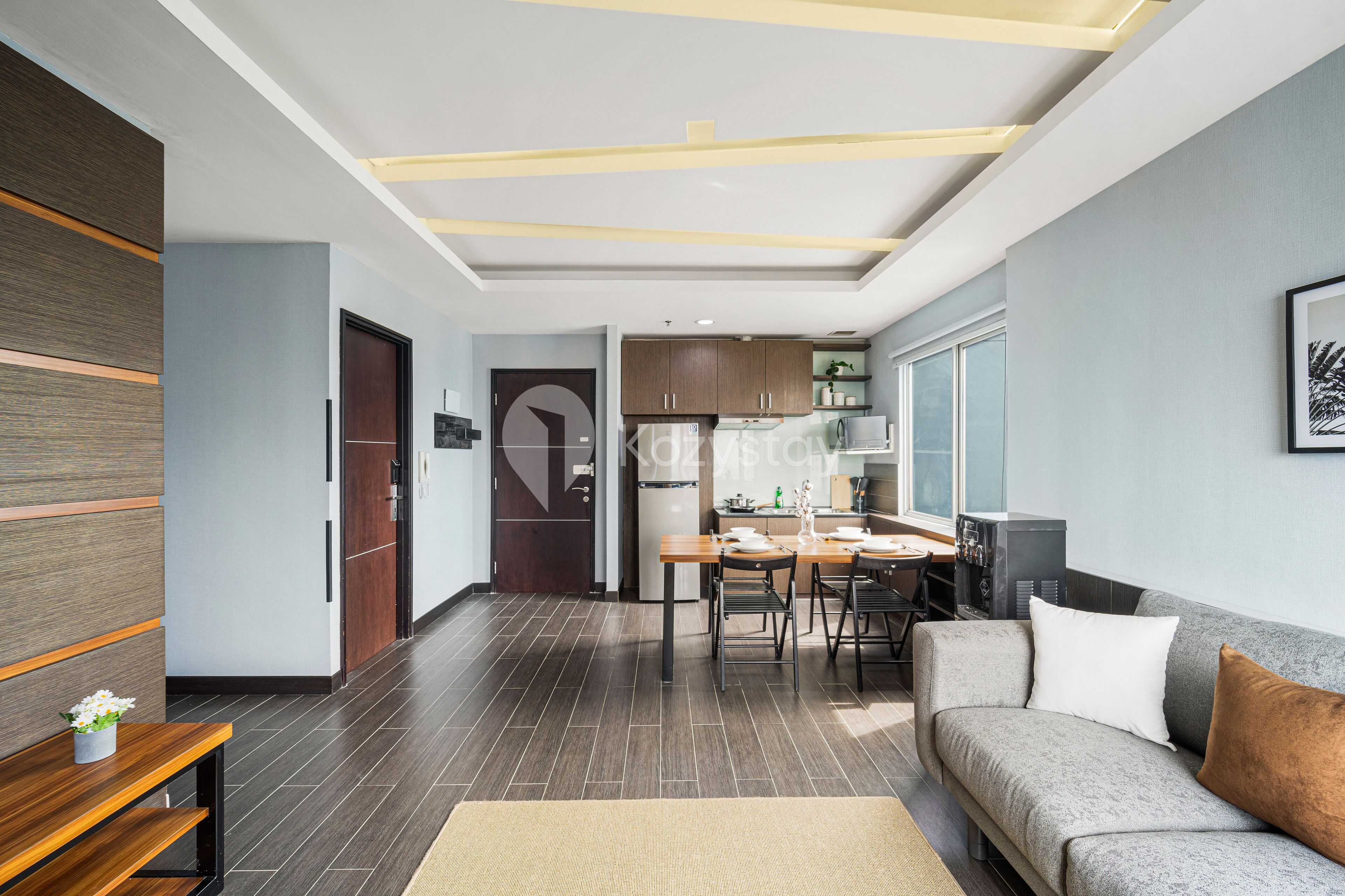 Una sala de estar moderna con un sofá gris, una mesa de centro de madera y un comedor con una mesa y sillas de madera.