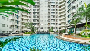 A swimming pool with a checkered pattern, surrounded by a multi-story building with balconies. - PECAN by Kozystay (Jakarta)