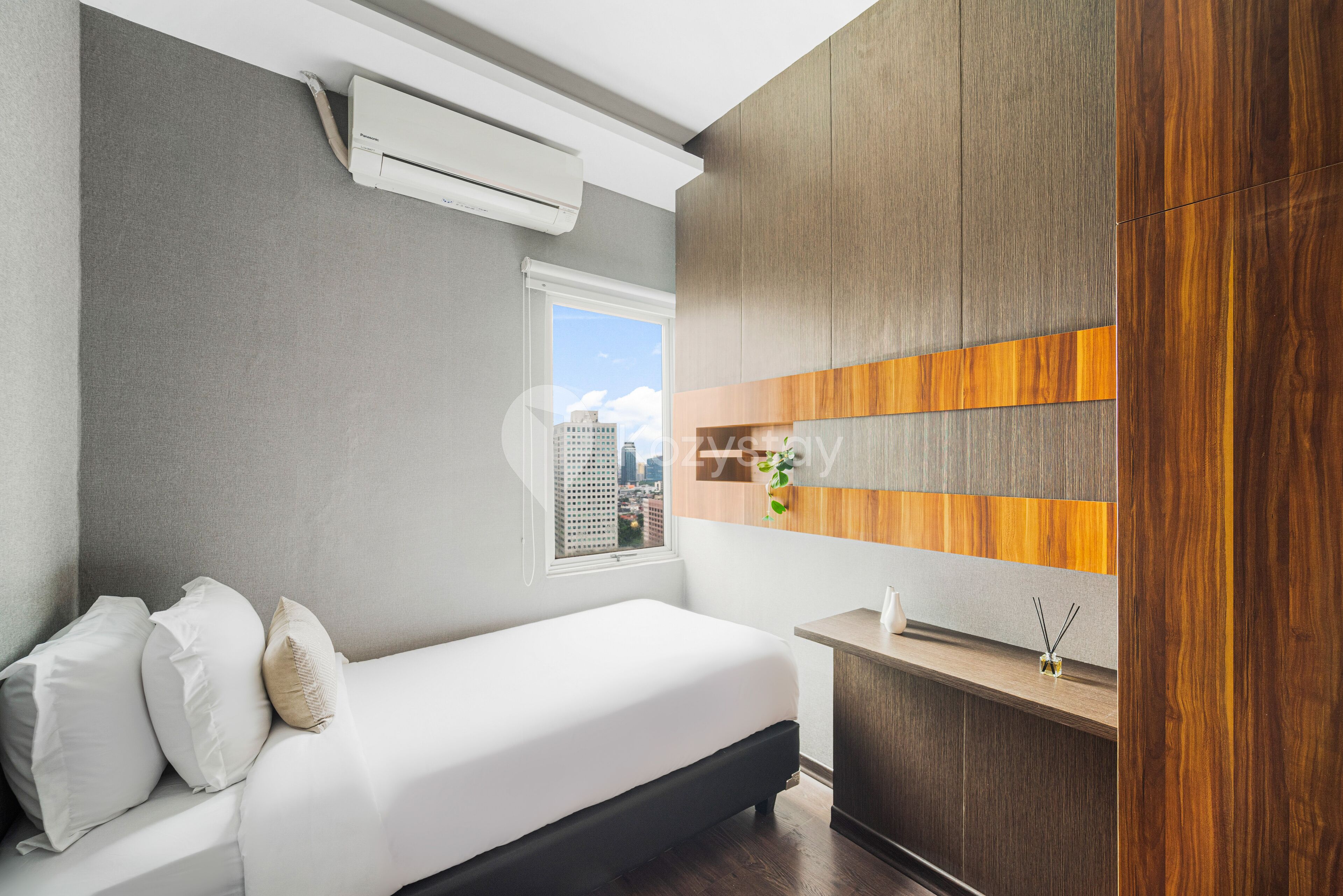 A modern bedroom with a bed, air conditioning unit, window, and a wooden panel wall.