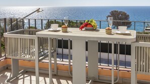 Ein Balkon mit Tisch für zwei Personen, mit Blick auf eine schöne Meereslandschaft.