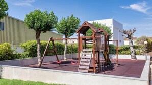 Un parque infantil con una estructura de madera para escalar y columpios.