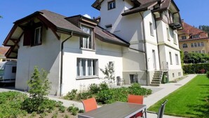 A two-story house with a balcony, a staircase, and a small garden area with a table and chairs. - Henry's 300 by Interhome (Interlaken)