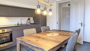 A modern kitchen with a wooden dining table, chairs, and pendant lighting. - Henry's 300 by Interhome (Interlaken)