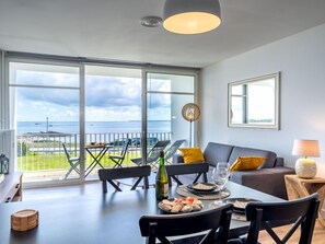 Een eethoek met uitzicht op zee, een bank en een lamp.