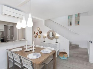 A modern kitchen with white cabinetry, a stainless steel refrigerator, and pendant lighting.