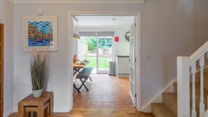 A hallway with a wooden bench, a potted plant, and a dining area with a table and chairs. - Sea Echo by Interhome (Charlestown)