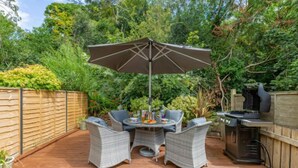 An outdoor patio with wicker furniture, a barbecue grill, and a large umbrella. - Sea Echo by Interhome (Charlestown)