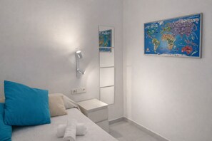 A bedroom with a bed, a nightstand, a wall-mounted lamp, a map, and a mirror. - Beautiful And Bright Apartment In Calafell, (Calafell)