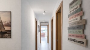 Un couloir avec un bureau en bois, un tableau encadré accroché au mur et un panneau avec du texte.