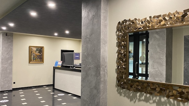 A reception area with a modern design, featuring a reception desk, a large mirror with an abstract frame, and a painting on the wall. - Batesta Hotel (Tbilisi)