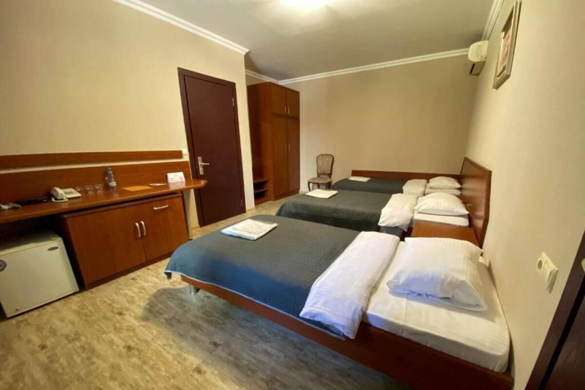 A hotel room with two beds, a desk, a chair, and a small refrigerator.