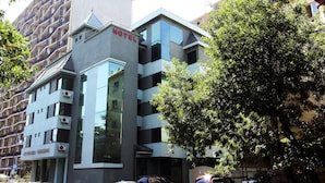 A modern hotel with a prominent 'HOTEL' sign, multiple balconies, and a parking area with several cars. - Batesta Hotel (Tbilisi)