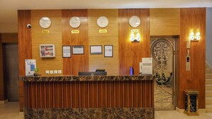 A reception desk with clocks indicating Tokyo, Riyadh, London, and New York. - Tura Residence Qurtuba (Riyadh)