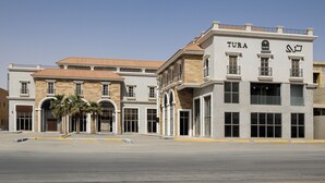 A multi-story building with a tiled roof, large windows, and a sign that reads "TURA". - Tura Residence Qurtuba (Riyadh)