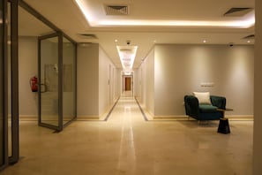 Experience a welcoming atmosphere in our sleek corridor, featuring a seating area for relaxation and a polished floor.